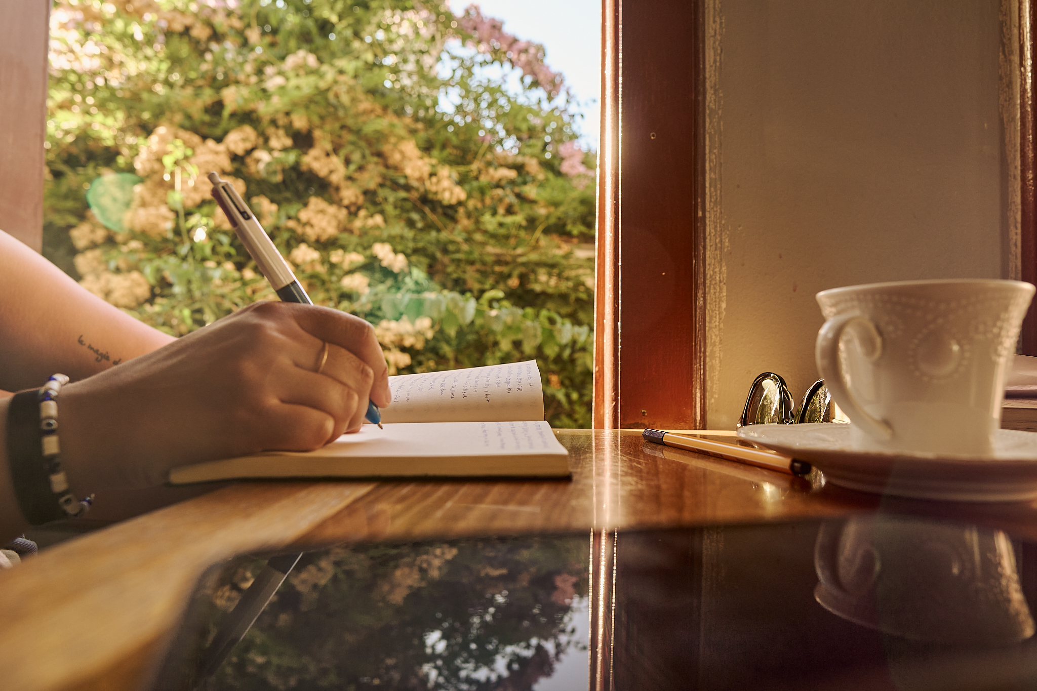 Hand writing in a journal beside a cup of coffee